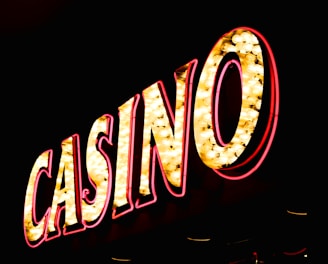 Brightly illuminated letters spell out 'CASINO' with glowing yellow bulbs and red outlines against a dark background.
