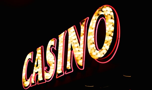 Brightly illuminated letters spell out 'CASINO' with glowing yellow bulbs and red outlines against a dark background.